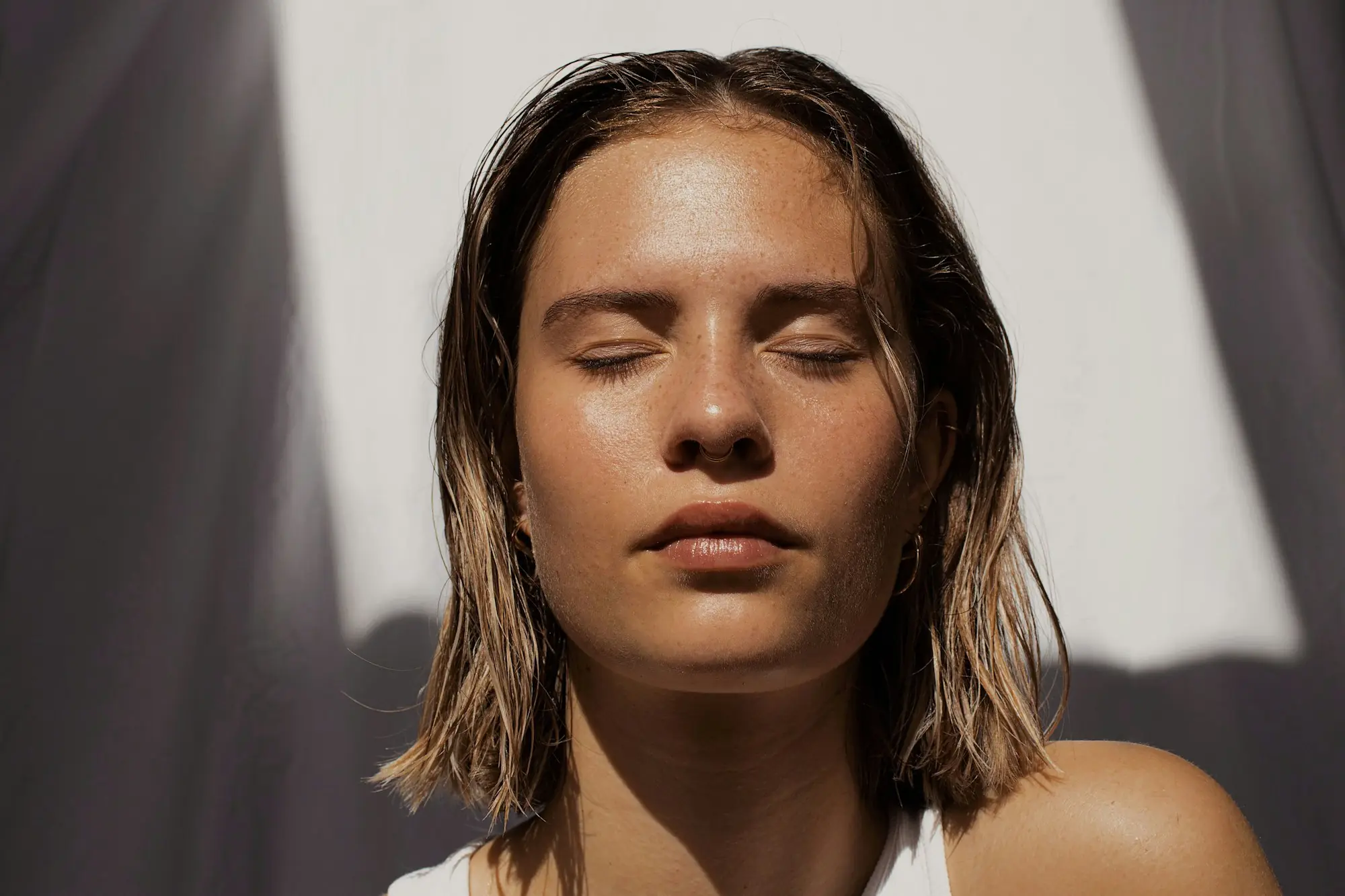 A woman with fresh, natural-looking skin, eyes closed in soft daylight